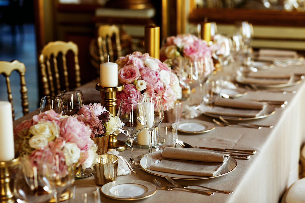 Long table served with porcelain crockery and shining cutlery served with pink flowers